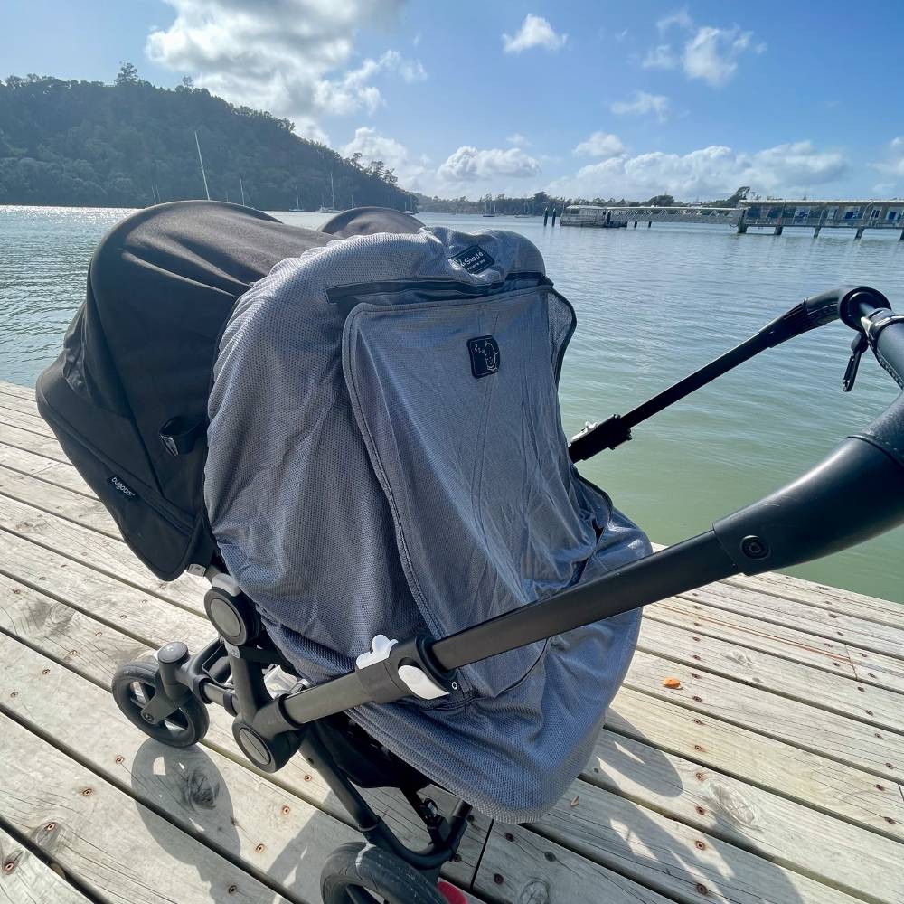 Stroller with a Twin Snoozeshade cover on a wooden dock by a body of water