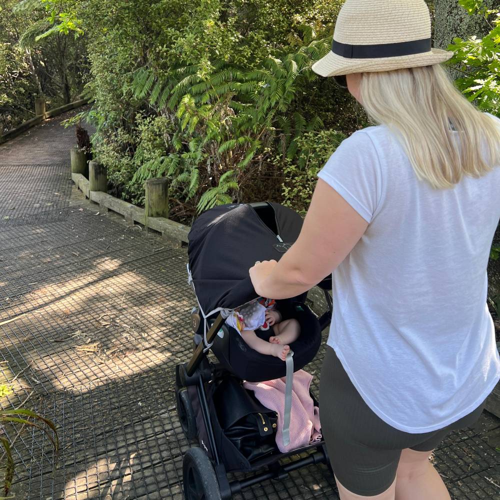 Woman pushing a stroller with a child in a park setting