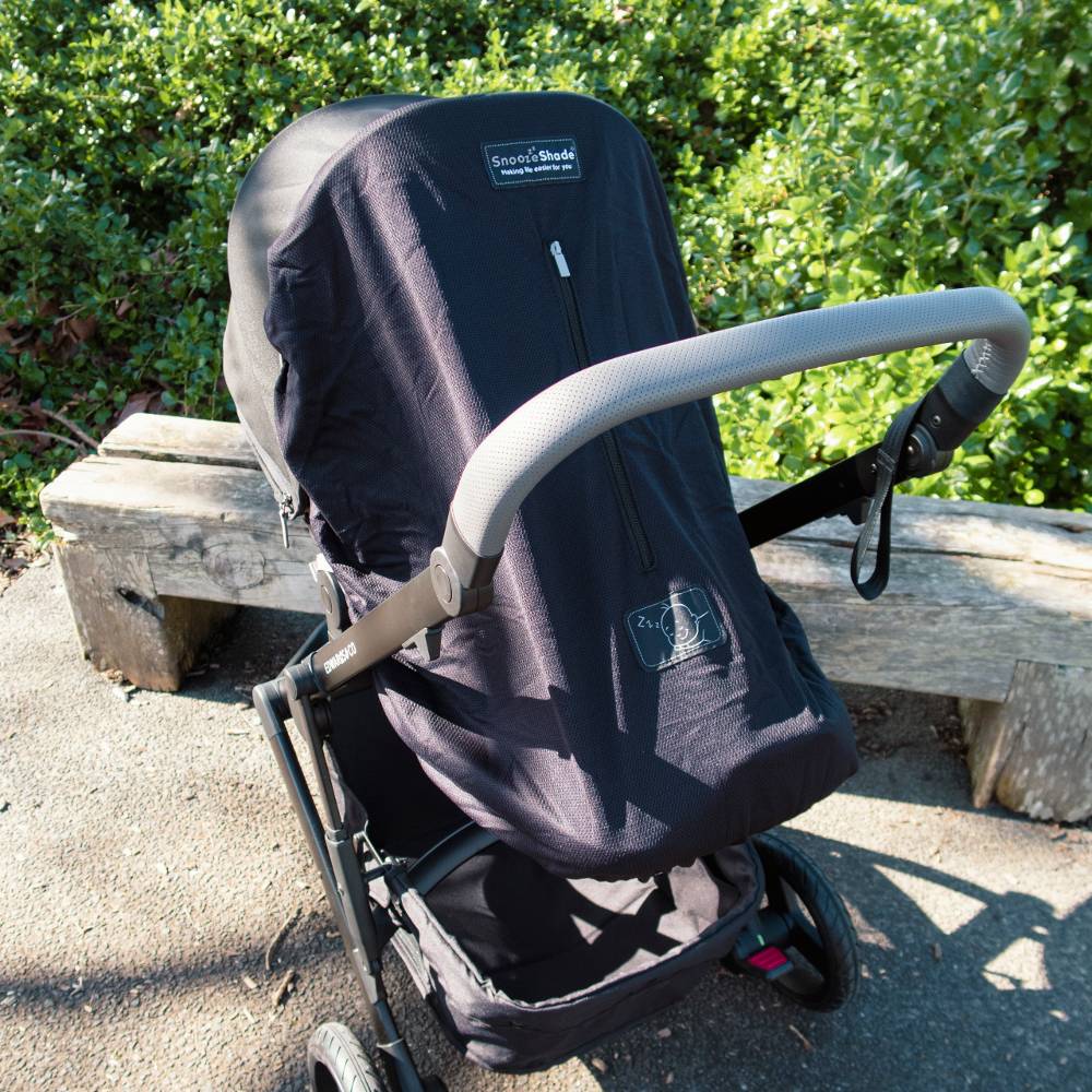 Black SnoozeShade stroller on a wooden bench outdoors