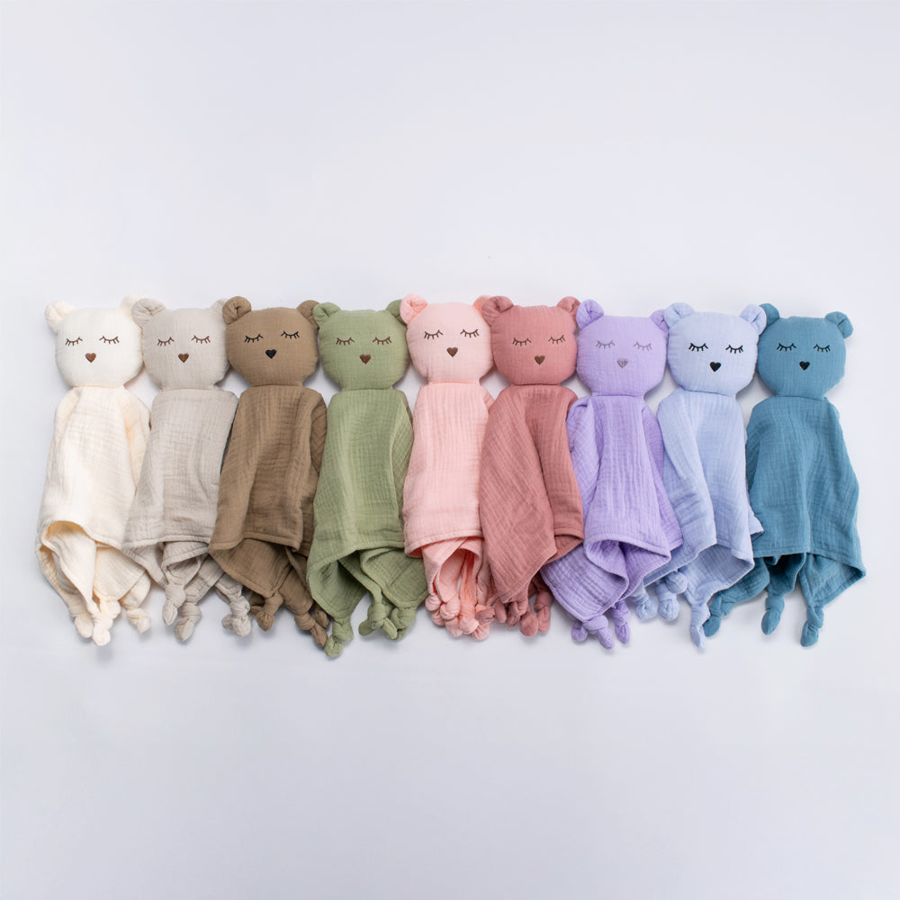 Row of colorful baby comforter with bear faces on a light gray background