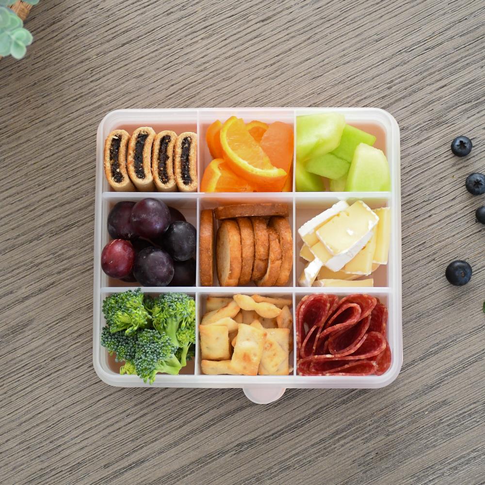 Assorted snacks in a compartmentalized container on a wooden surface