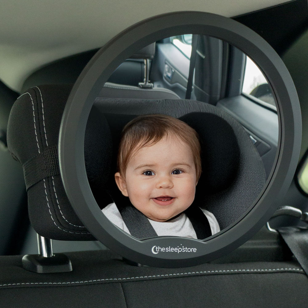 Baby in a car seat reflected in a mirror with 'thesleepstore' branding.