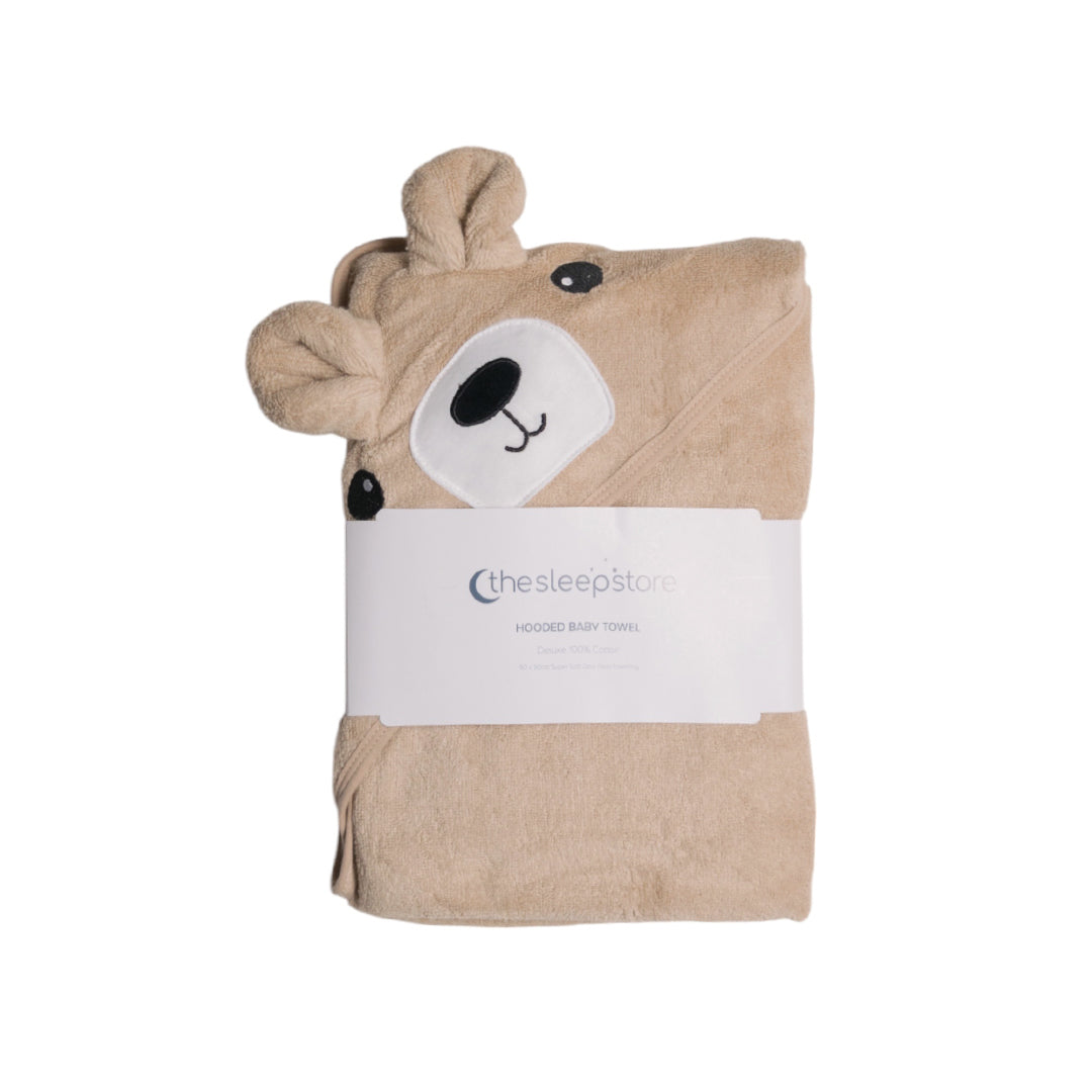 A folded beige hooded baby towel with a bear face hood, wrapped in a white paper band that reads 'thesleepstore'.