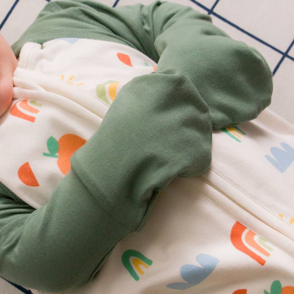 Green baby mitten sleeves with a white and colorful patterned sleeping bag on a white background
