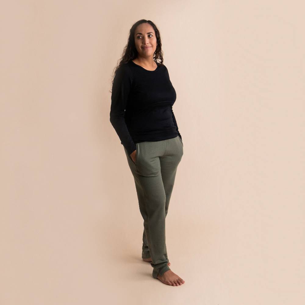 Woman wearing a black Merino/Tencel Breastfeeding top and green pants against a beige background