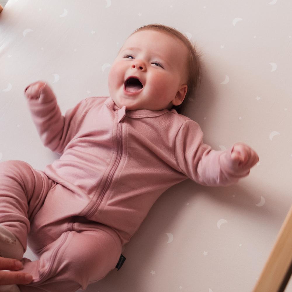 Baby in a merino zipsuit lying on a soft surface