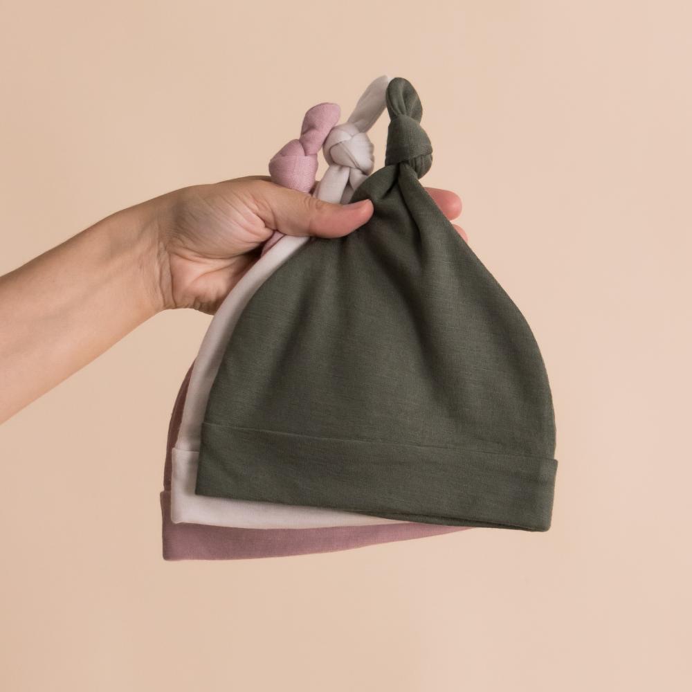 Stack of Merino knotted baby beanies in olive, white and pink
