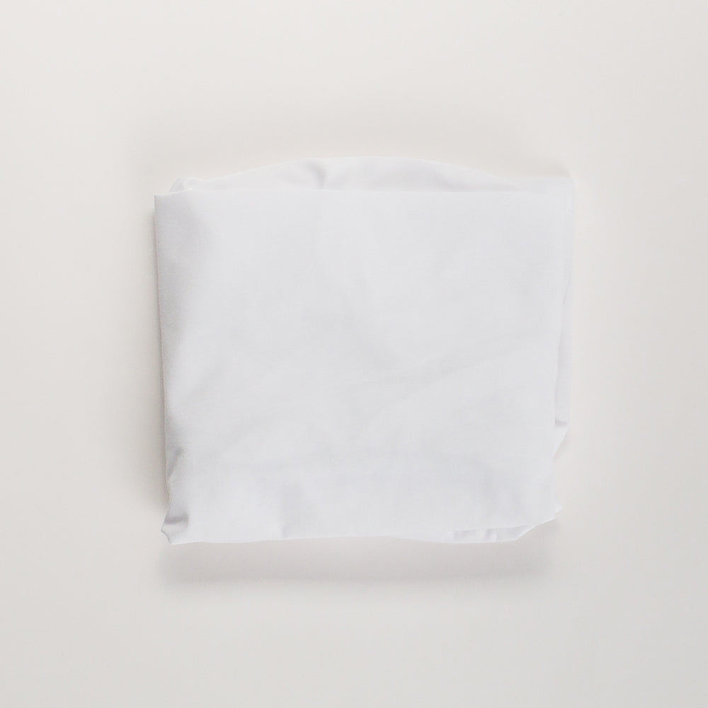 A plain white folded cotton fabric or centered on a light off-white background.
