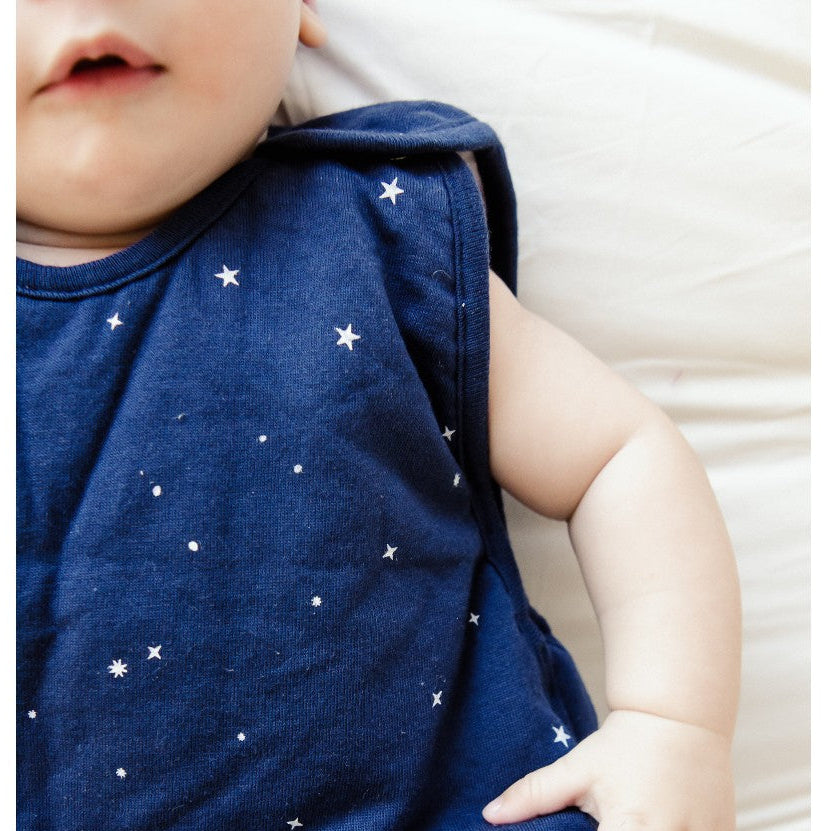 Baby wearing a navy blue outfit with star patterns on a white background