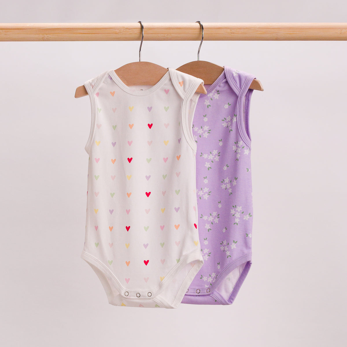 Hanging shot of 2 singletsuits. Mini hearts and Lilac Daisy. 