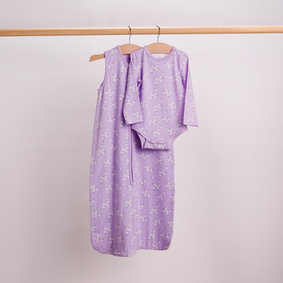 Hanging shot of a matching set in the Lilac Daisy print. A baby sleeping bag and long sleeve bodysuit. 