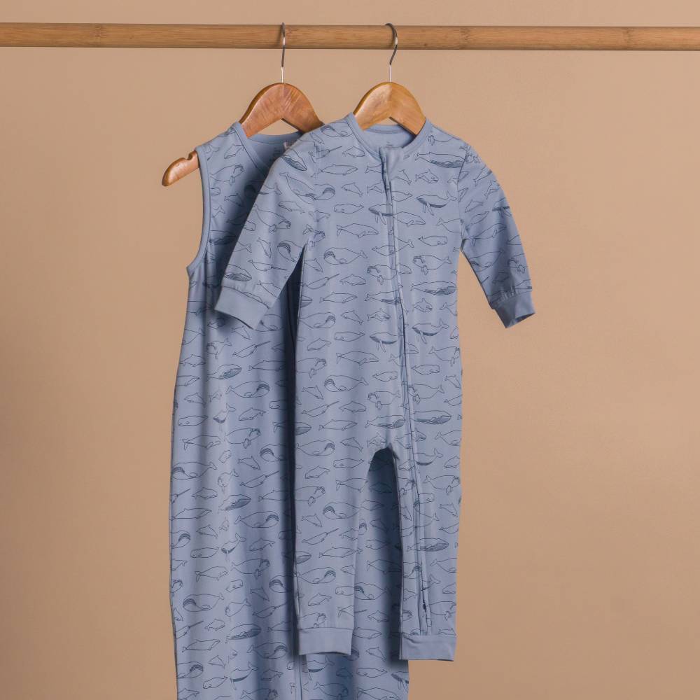 Blue patterned baby onesie on a hanger against a beige background
