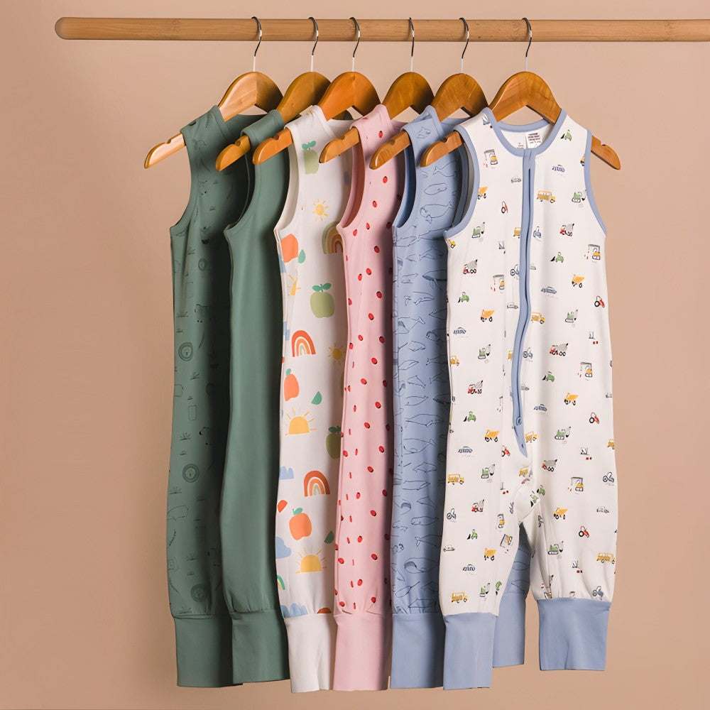 Set of colorful baby sleepsuits on wooden hangers against a beige background