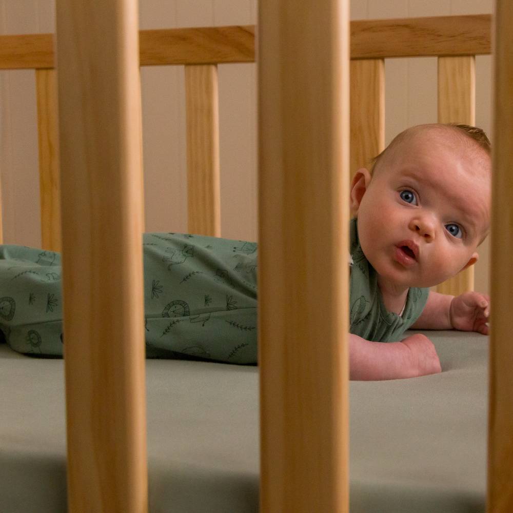 Baby lying in a crib with wooden bars