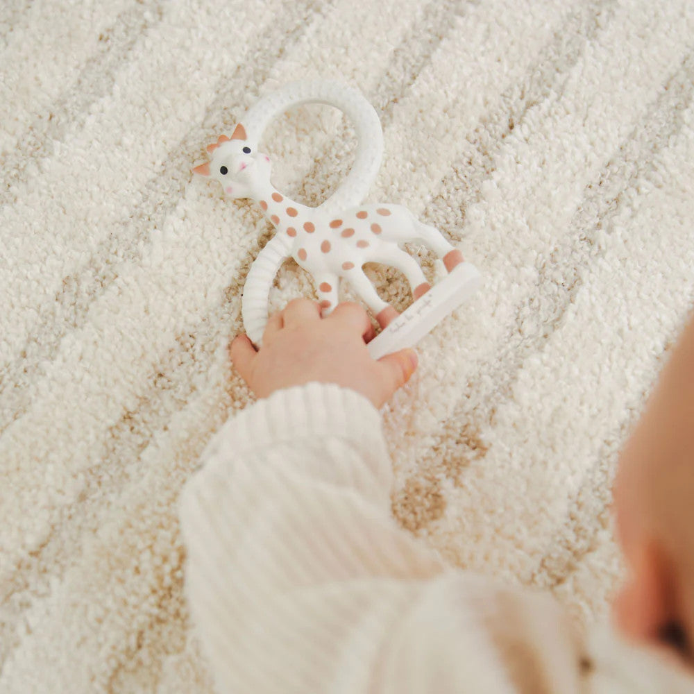 A baby hand holding a Sophie La Giraffe - Teething Ring. 