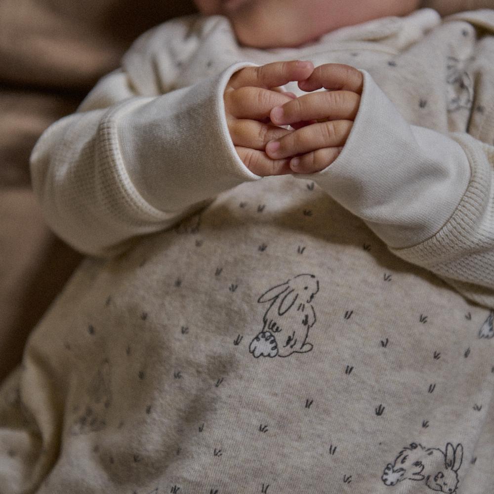 Close-up of a child's hands in a beige sleeping bag with soft bunny design