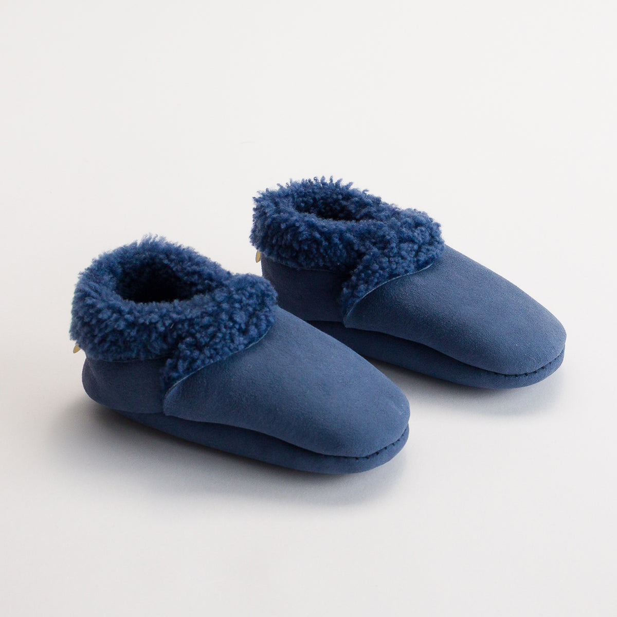 Pair of blue woolbabe lambskin booties with fuzzy trim on a white background