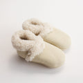 Pair of cream-colored lambskin wool baby booties with fluffy trim on a white background