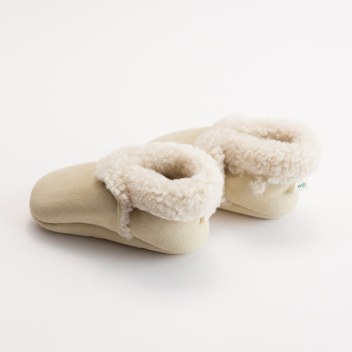 Pair of beige slippers with sherpa lining on a white background