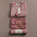 Folded baby clothing set with 'woolbabe' label on a beige background