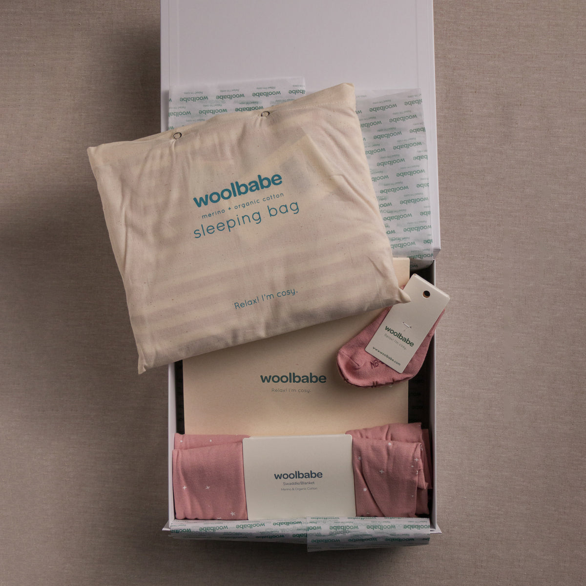 woolbabe sleeping bag and blanket set in packaging on a brown surface