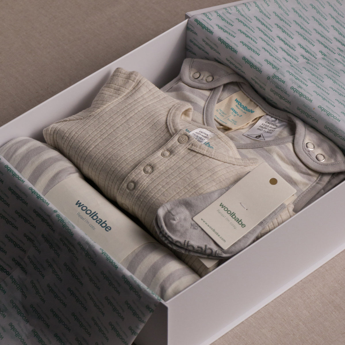 Baby clothing set in a gift box with 'woolbabe' branding.