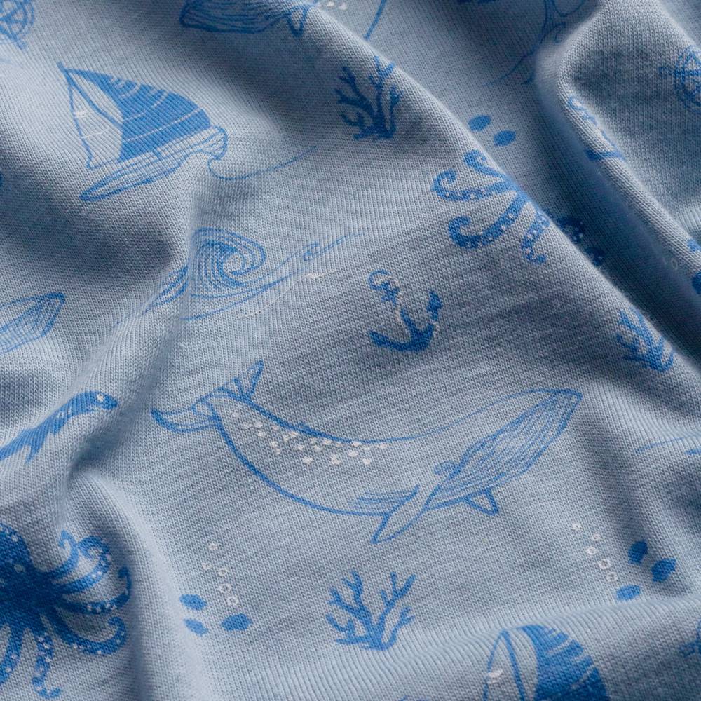 Close-up of merino swaddling blanket with blue sea-themed patterns on a gray background
