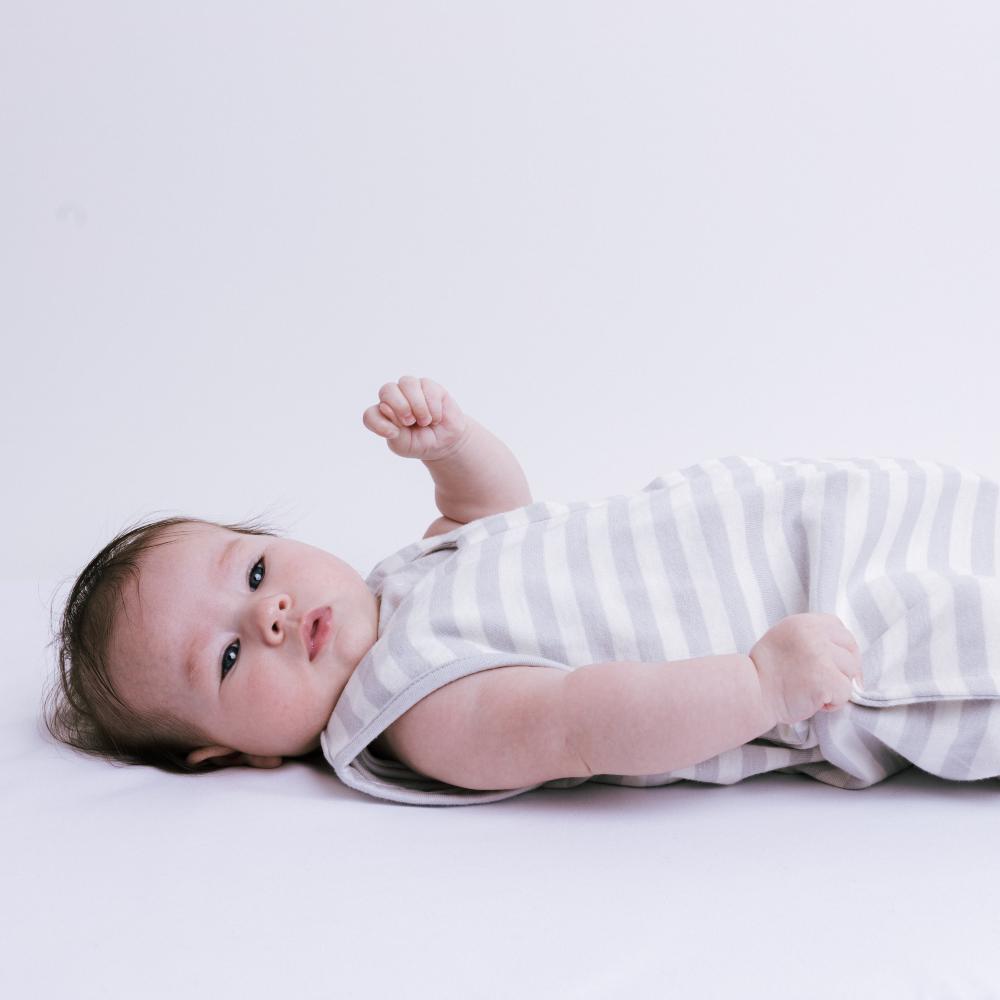 Baby lying on a white surface wearing a striped outfit