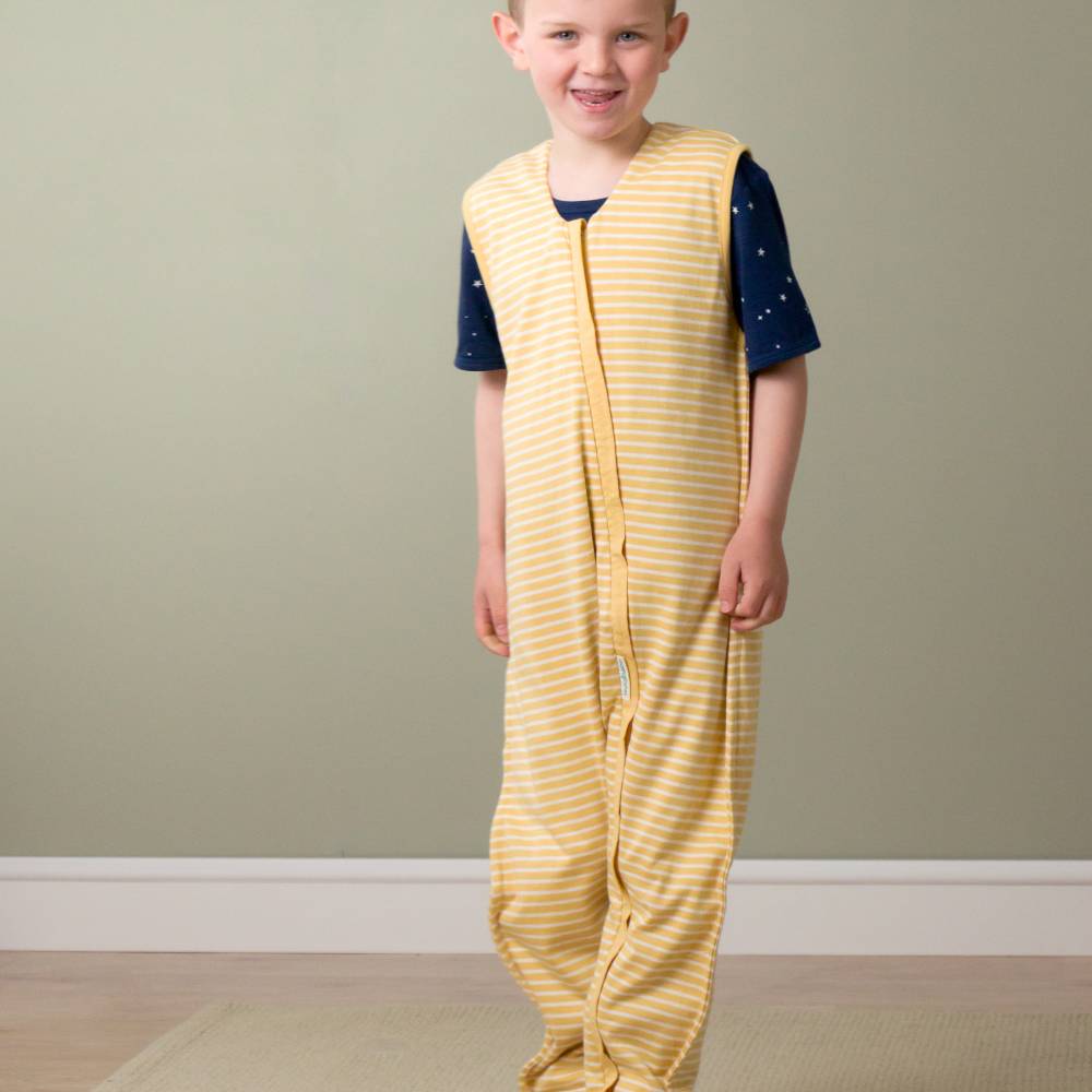 Child wearing a yellow striped outfit with a navy blue top against a plain wall.