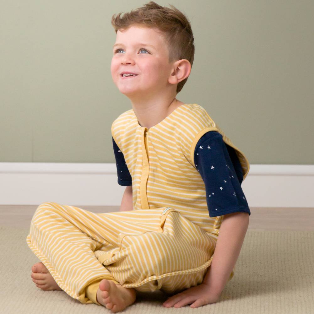 Child wearing a yellow and navy striped outfit sitting on the floor.