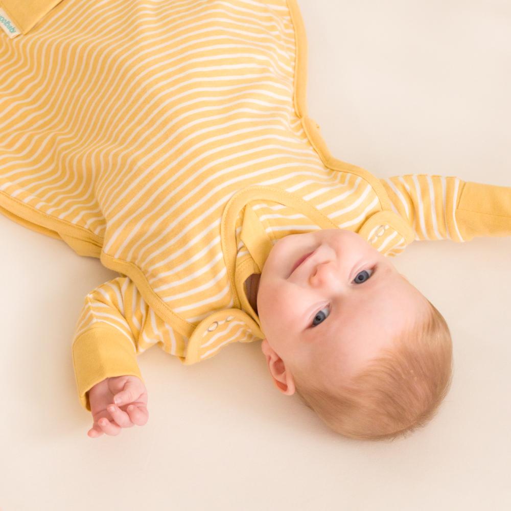 Baby wearing a yellow and white striped onesie on a light beige background