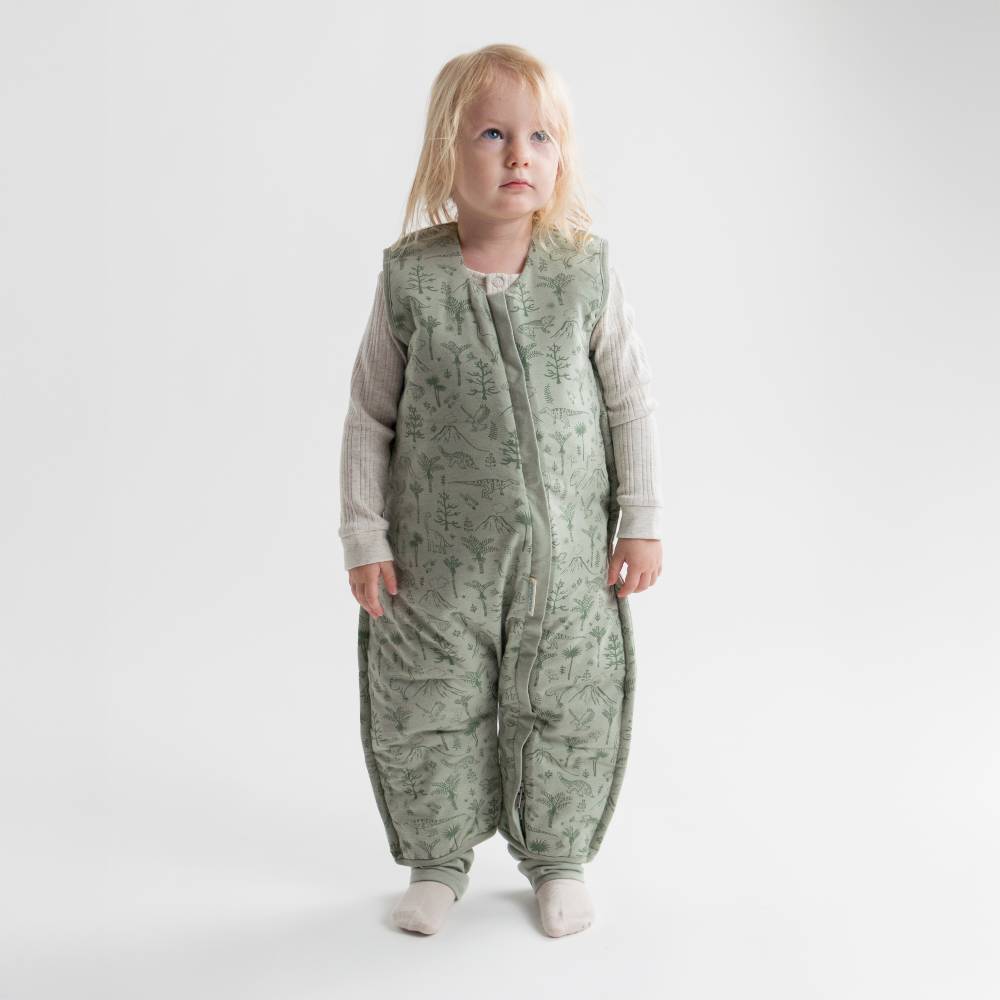 Child wearing a green patterned sleep onesie against a white background
