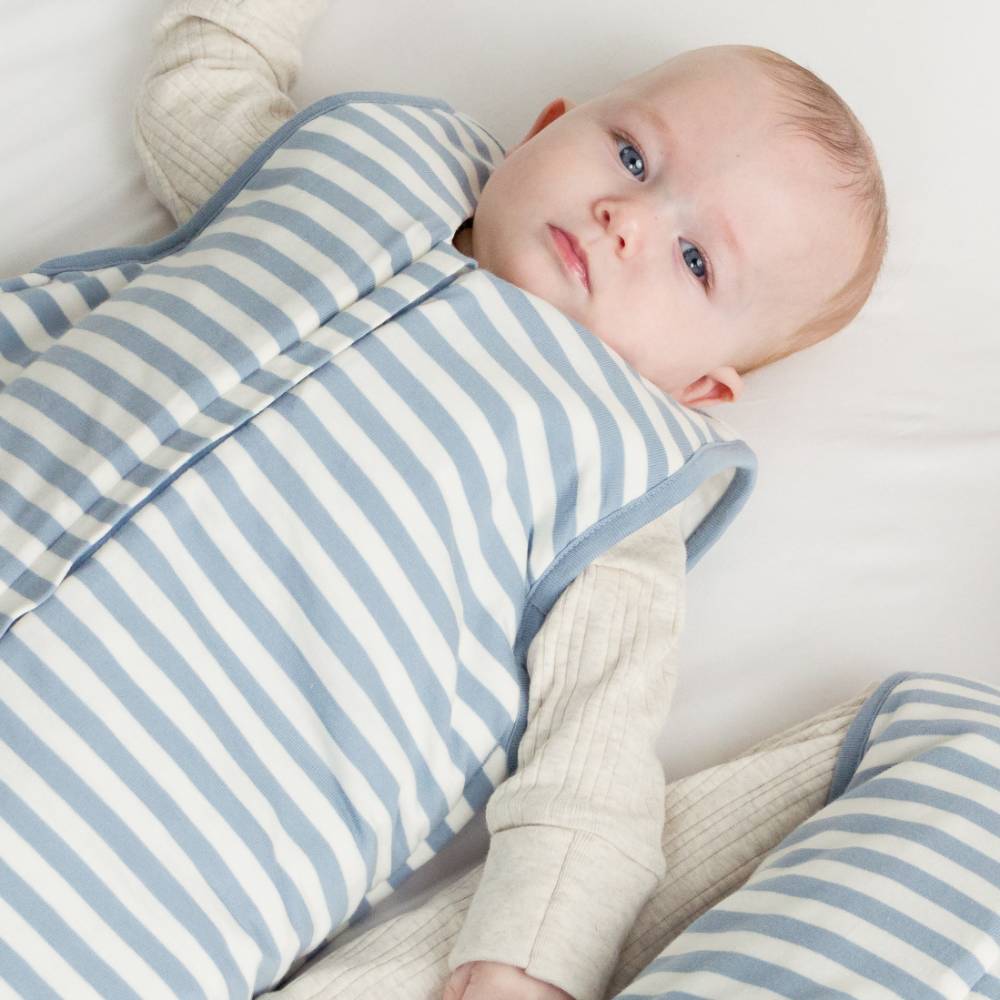Baby wrapped in a blue and white striped swaddle on a white background