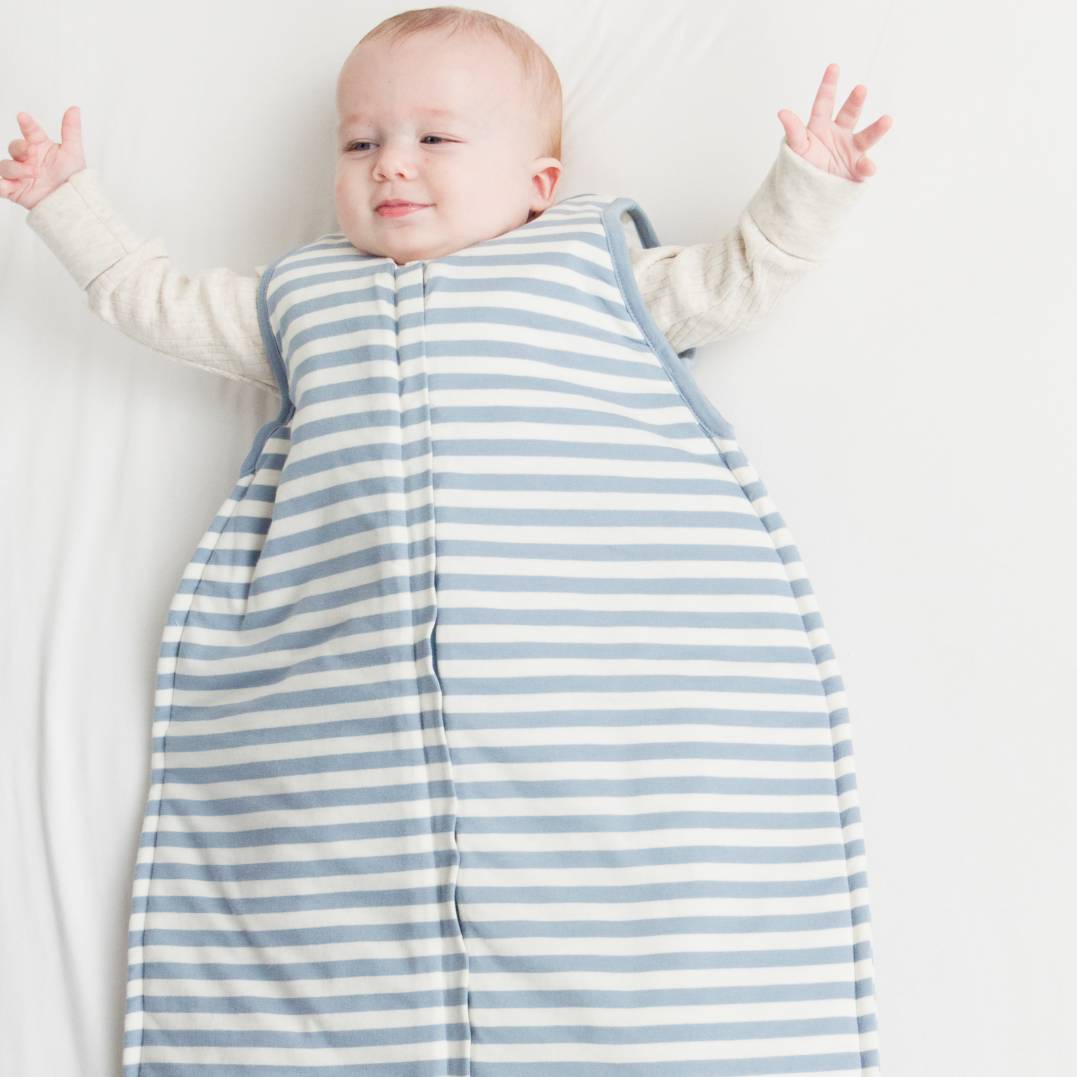 Baby wearing a blue and white striped sleep bag on a white background