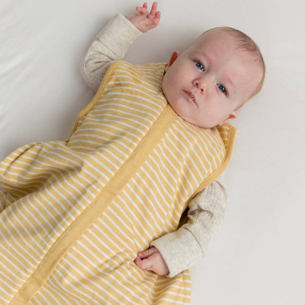 Baby wearing a yellow and white striped outfit on a plain background