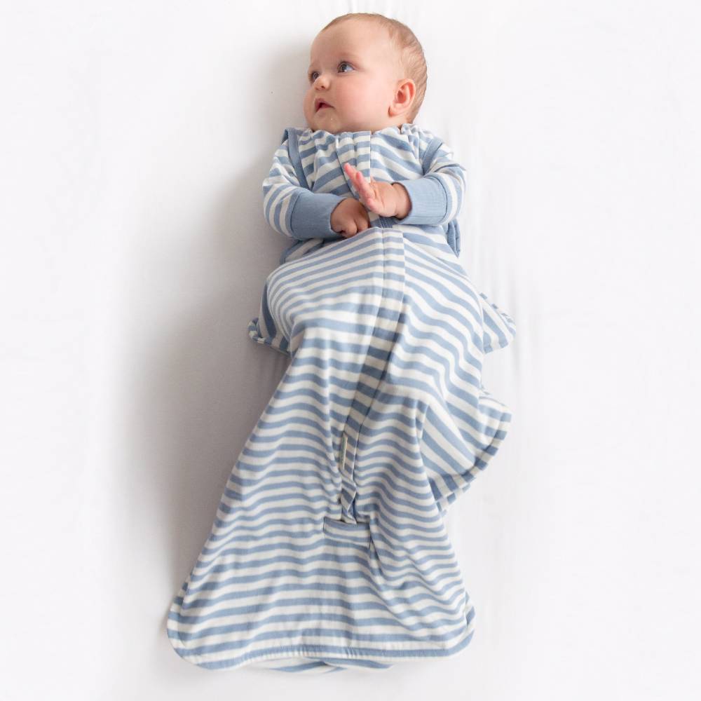 Baby wrapped in a blue and white striped sleep sack on a white background