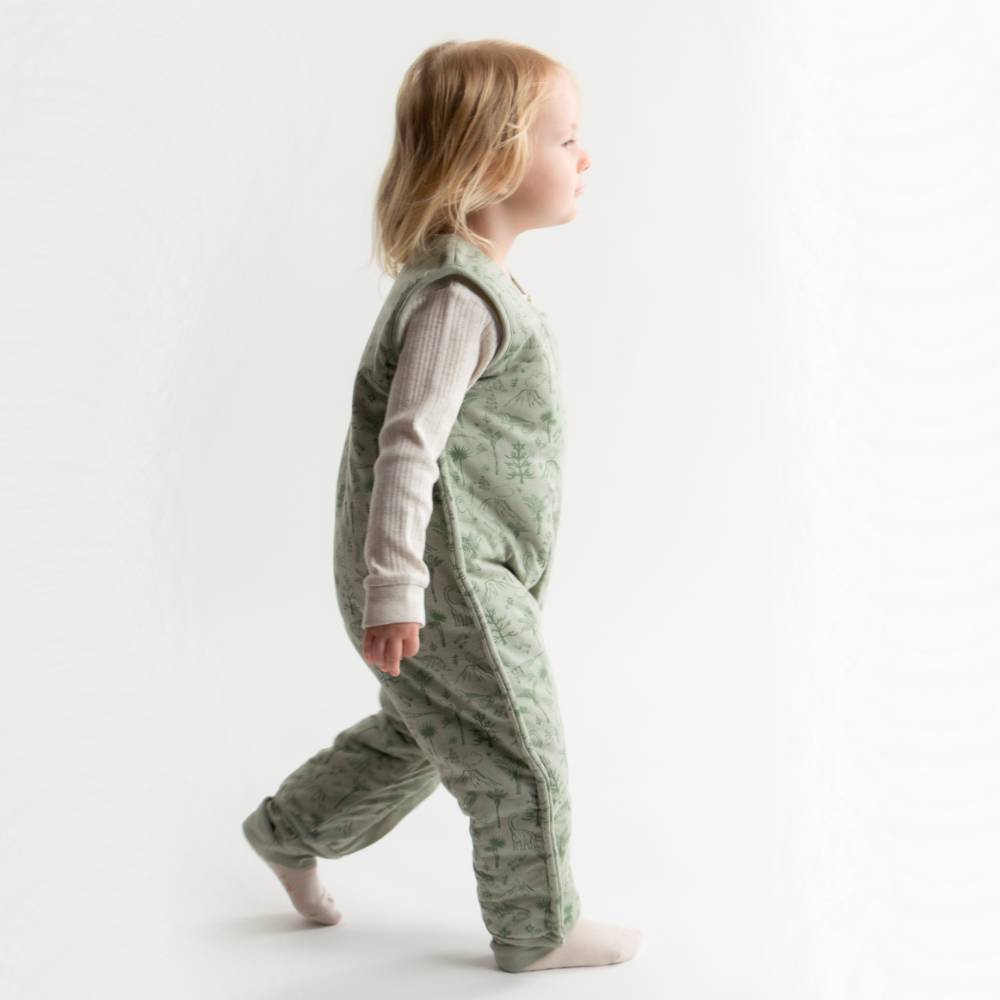 Child wearing a green merino sleepsuit on a white background