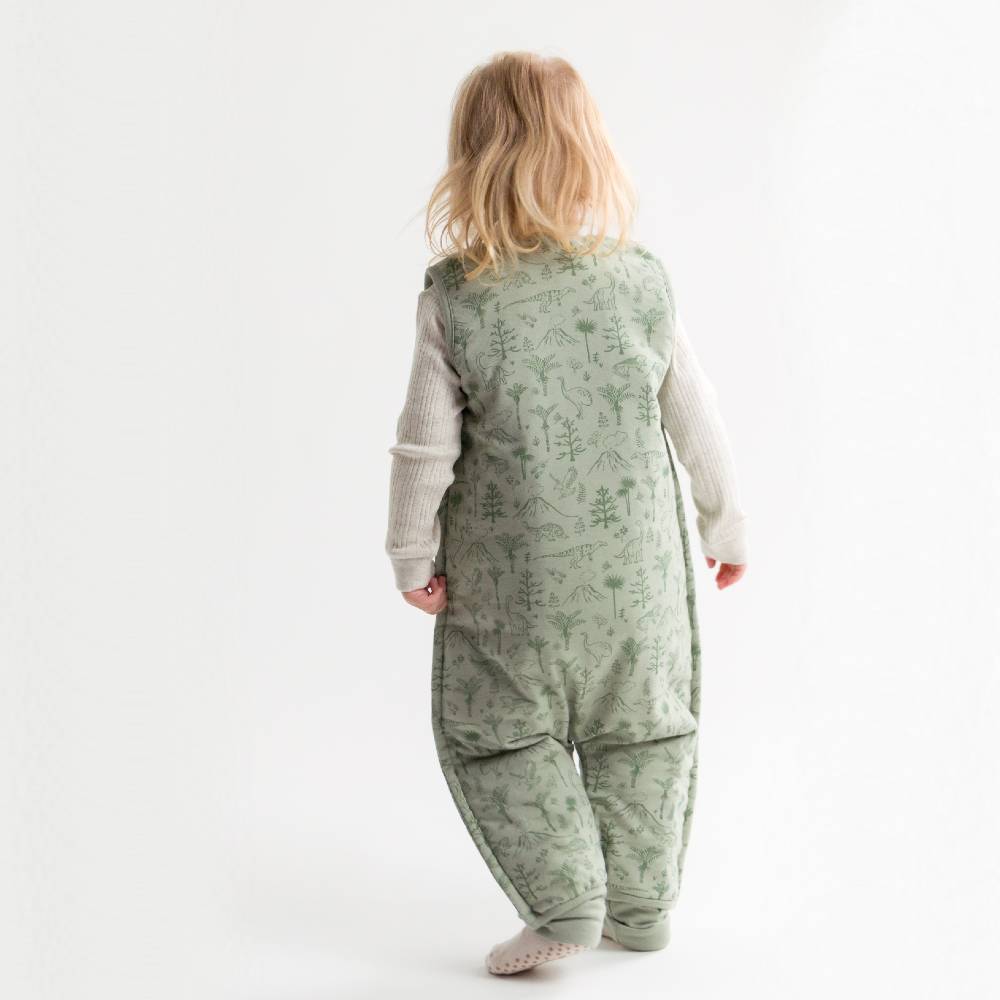 Child wearing a green patterned onesie on a white background
