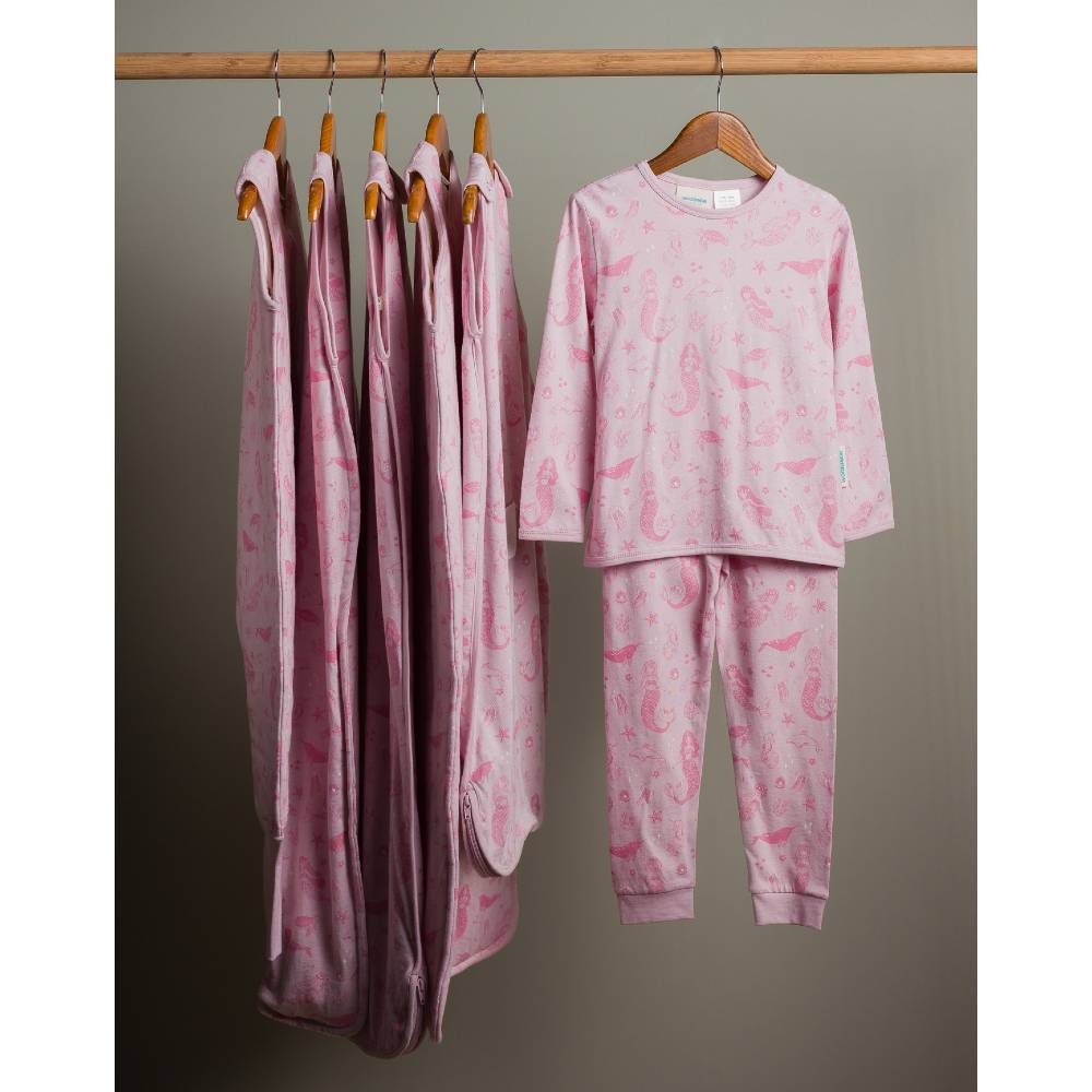Pink woolbabe Shell Mermaids collection and pajama set hanging on a rack against a gray background