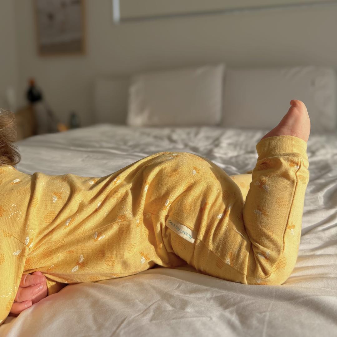 Child in yellow pajamas lying on a bed in a bedroom