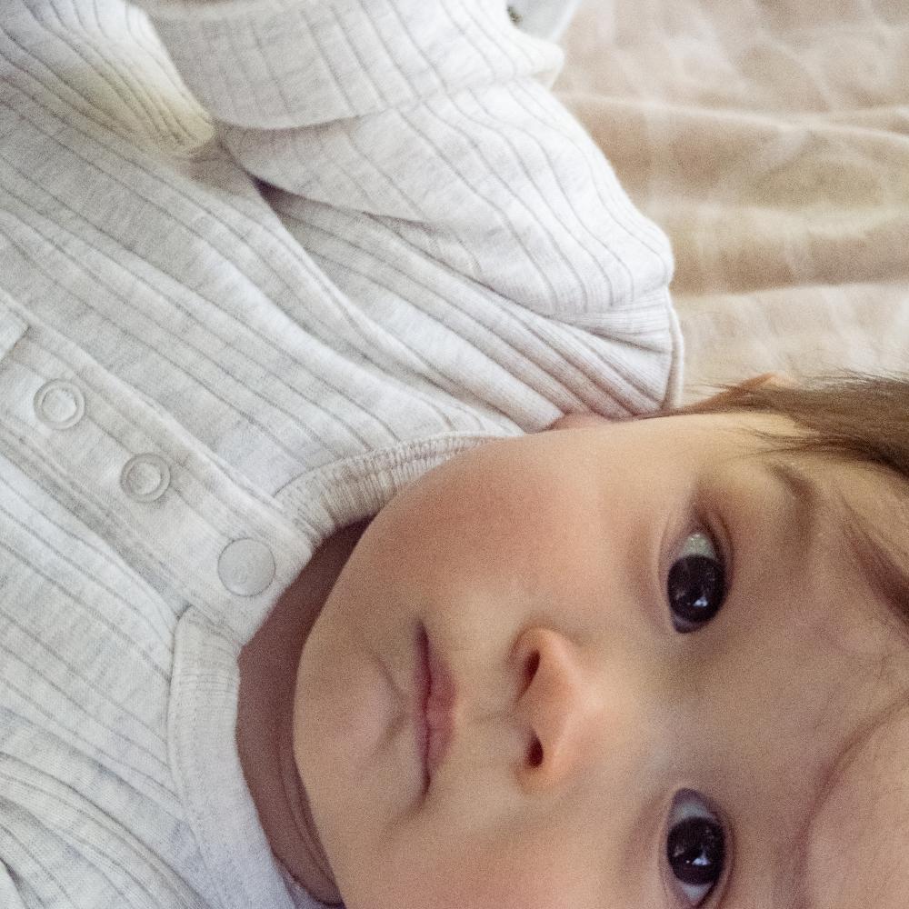 Close-up of a baby wearing a cream merino ribbed outfit from woolbabe
