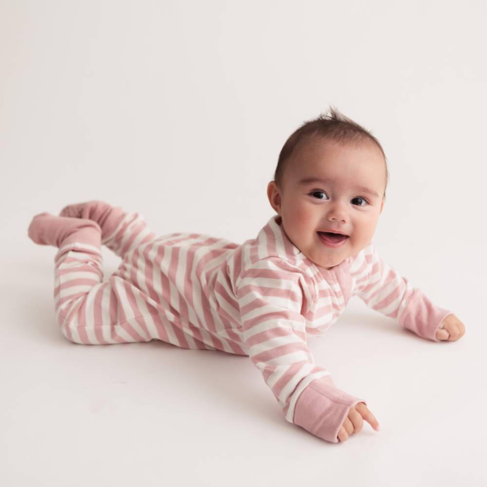 Baby wearing a pink and white striped onesie on a light background