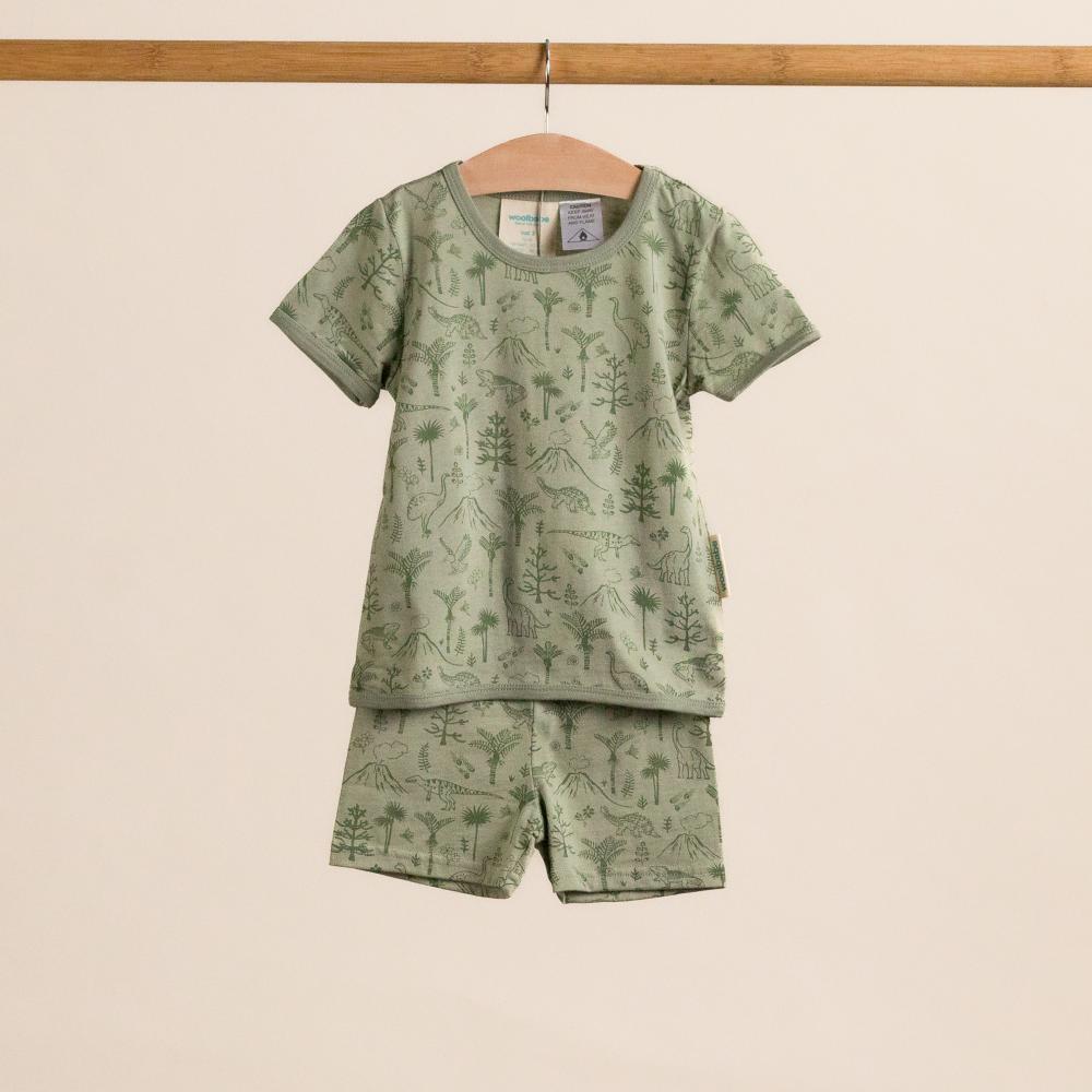 Children's green pajama set with nature-themed design on a beige background
