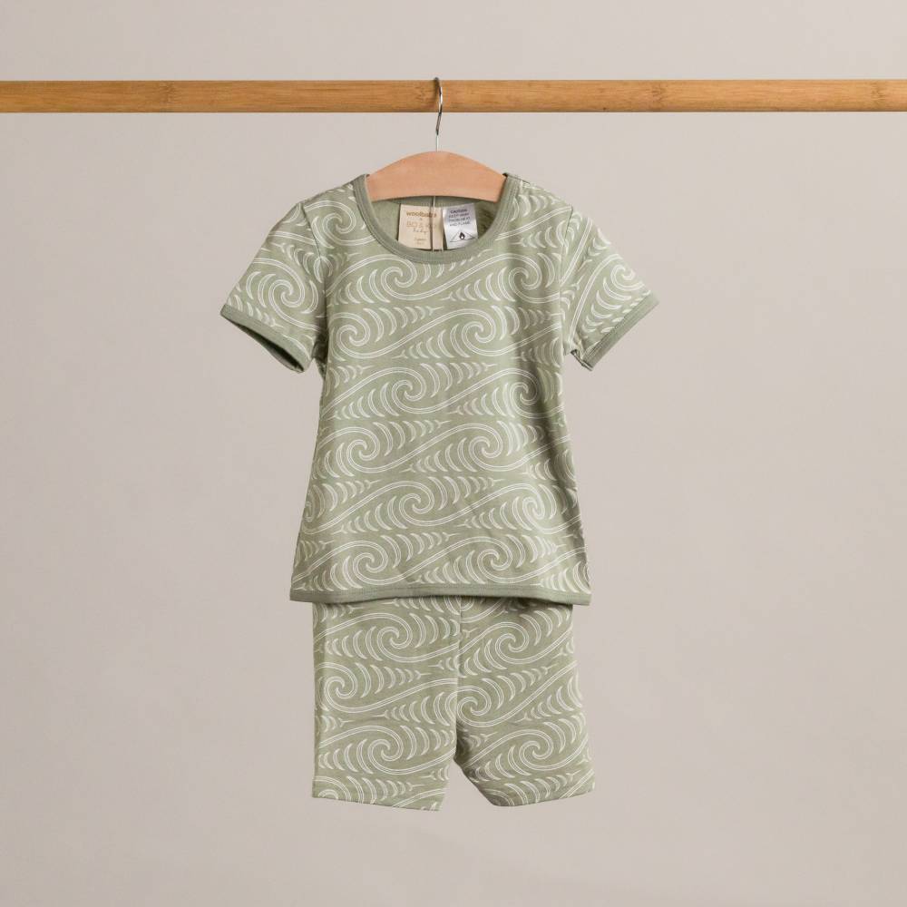 Green Maori patterned shirt and shorts set on a hanger against a plain background