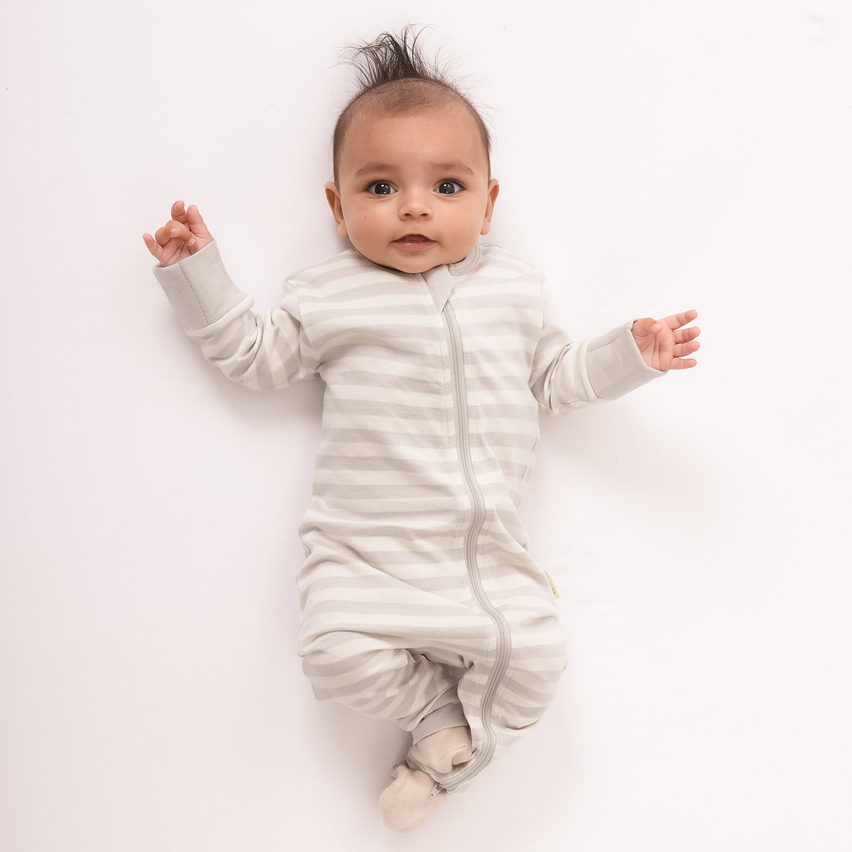 Baby wearing a white striped onesie on a light background