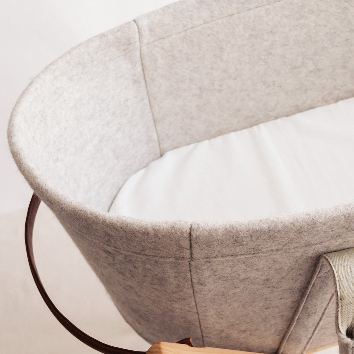 Close-up of a gray baby crib with white mattress on a light background