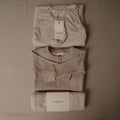 Folded baby clothing set with 'woolbabe' tags on a brown background