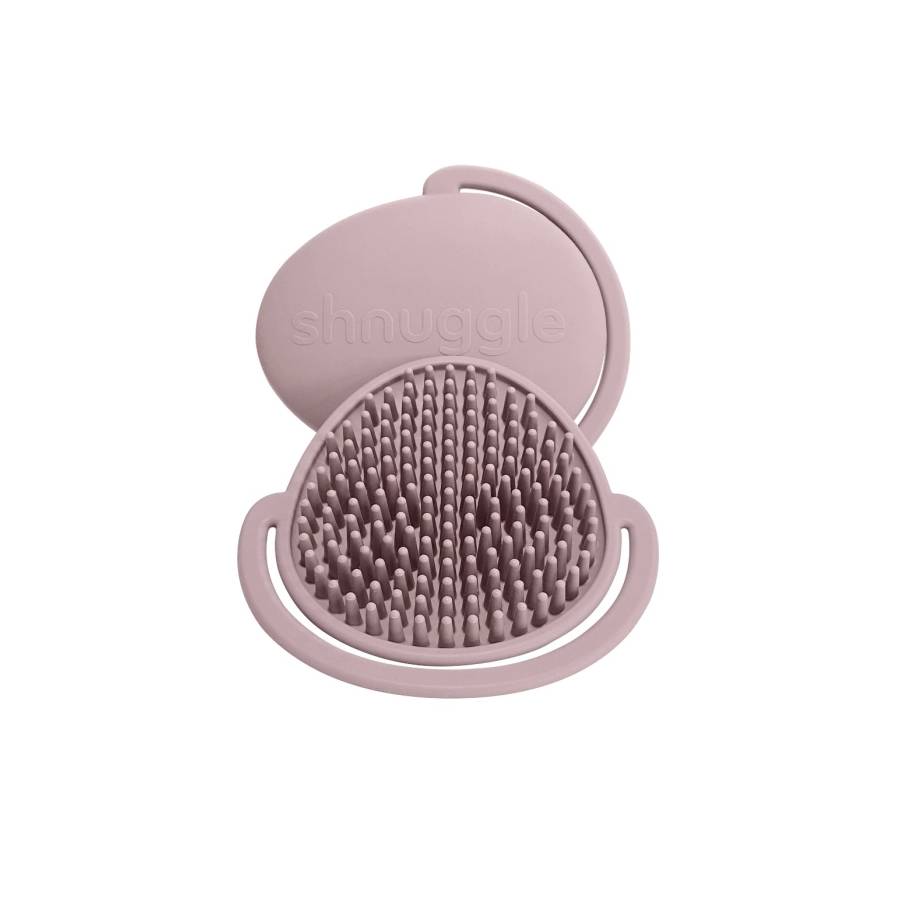 A dusty pink silicone scalp massager brush with a matching lid, shown open on a solid white background. The brand name 'shnuggle' is embossed on the lid.