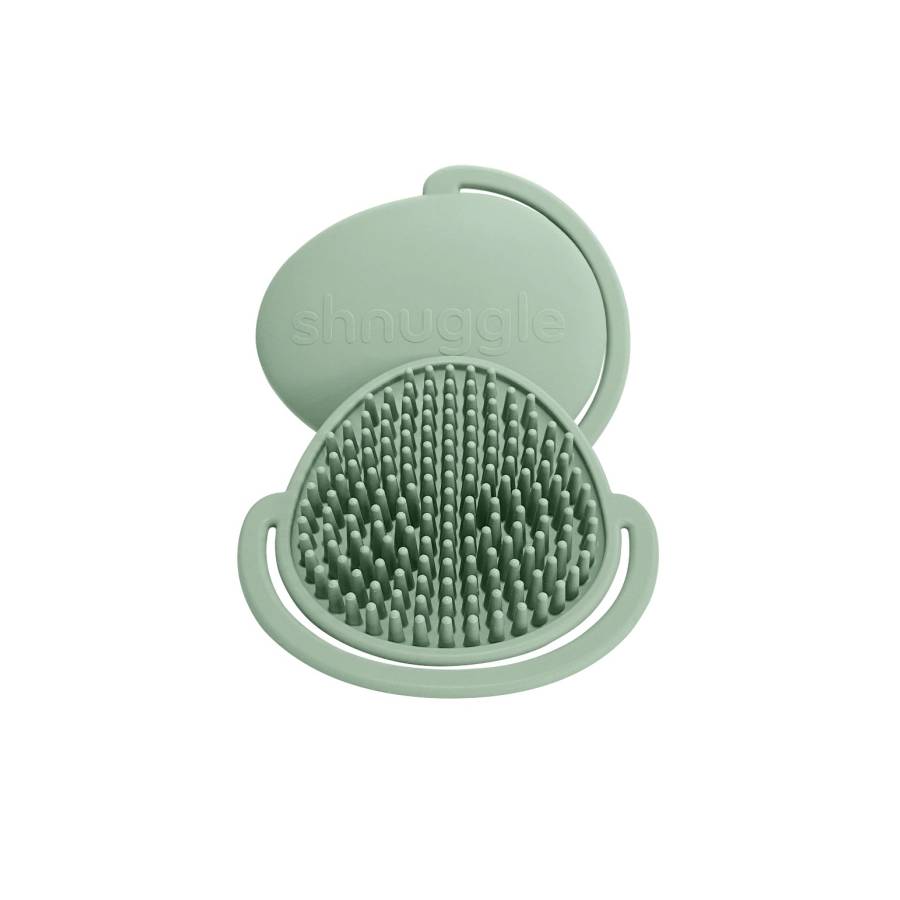 A green silicone scalp massager brush with a matching lid, shown open on a solid white background. The brand name 'shnuggle' is embossed on the lid.