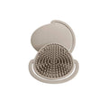 Beige silicone scalp brush with textured surface and smooth lid on a white background, branded 'shnuggle'.